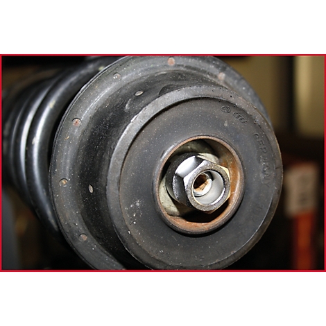 Nahaufnahme eines Stoßdämpfers mit Schraube, Unterlegscheibe und Feder. Schwarze Gummiteile.